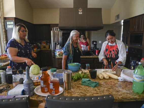 Diné College students Angel Leslie (left), Alyssa Joe (back) and program manager Kaitlyn Haskie (right) make fry bread and prepare mutton stew for a meal at the home of Kathleen Rodgers, PhD, who developed and leads the URBRAIN program.