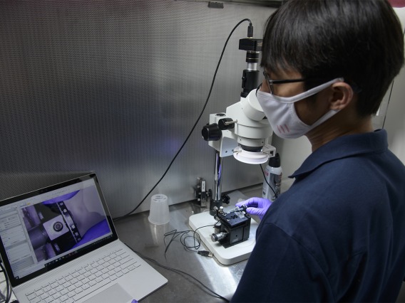 Dongkyun Kang, PhD, uses a microscope and laptop to assist his work on debugging the assembly of a new, handheld microscope to help diagnose skin cancer.