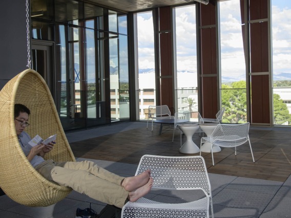 The Health Sciences Innovation Building is filled with cool and creative spaces to study, or just hang around – like this student on the sixth-floor open-air balcony where there are two hanging wicker chairs. 