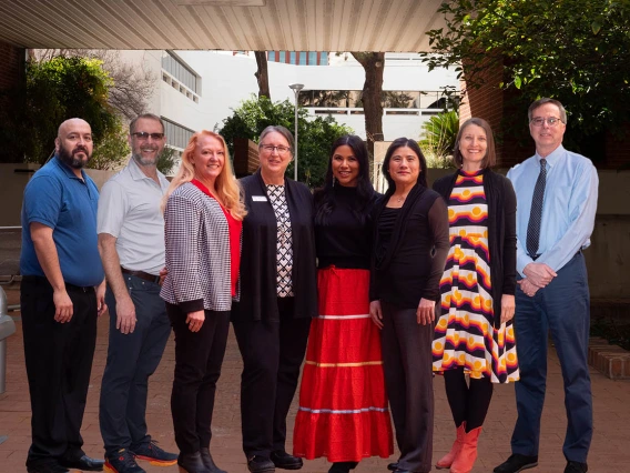 Eight nursing faculty stand side-by-side outside smiling.