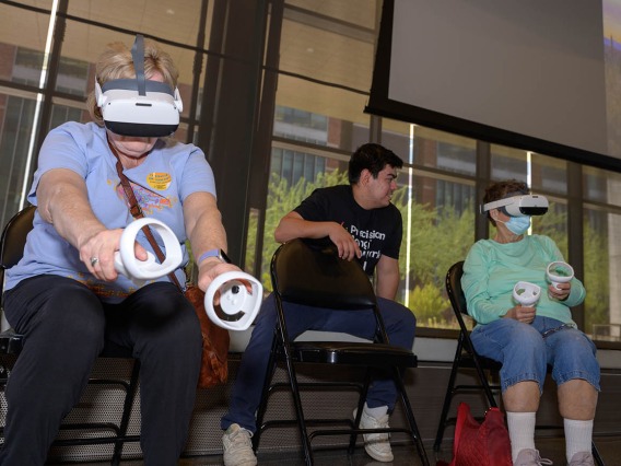 Attendees practice virtual reality tai chi while wearing VR headsets and holding touch controllers during the Feast for Your Brain community event on Sept. 10.