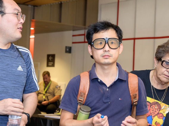 Attendees at the inaugural Feast for Your Brain event at the Health Sciences Innovation Building on Sept. 10 try on special eyeglasses that simulate macular degenerative disease. 