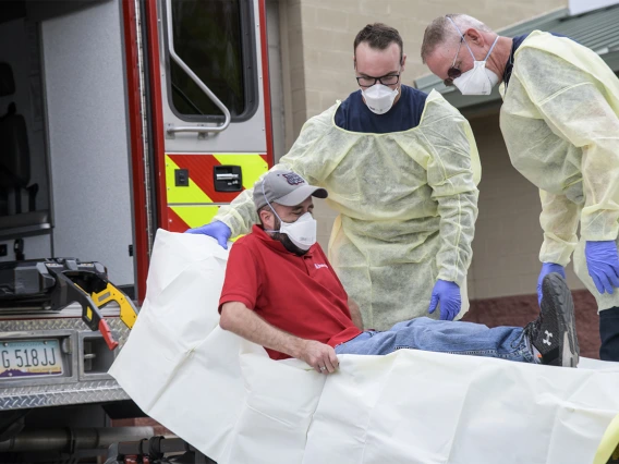 Firefighters Taylor Parish and Chris LaFave wrap Jonathan Sexton, PhD, in a protective barrier to demonstrate how to prevent the spread of a virus during an ambulance trip to the hospital. Sexton is a researcher in the Mel and Enid Zuckerman College of Public Health, participating in a training video in March to help first responders learn protective measures for possible COVID-19 patients.