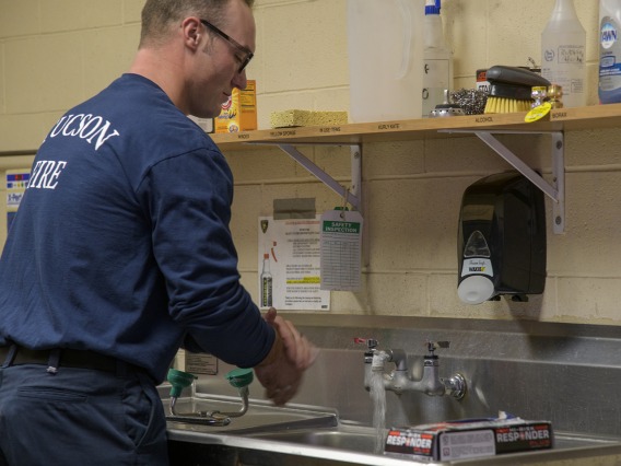 Tucson Fire Department’s Taylor Parrish washes his hands after sanitizing equipment as part of a training to help first responders prevent the spread of an infectious disease. 