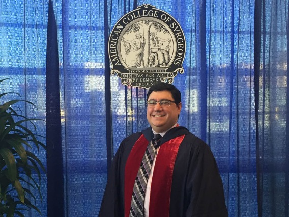 Middle-aged man with dark, short hair and glasses, wearing an academic gown under the American College of Surgeons seal