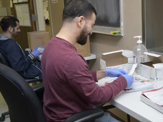 Biorepository laboratory techs Ayman Sam (left) and Brandon Jernigan (right) complete the final step to assemble the COVID-19 sample collection kit.