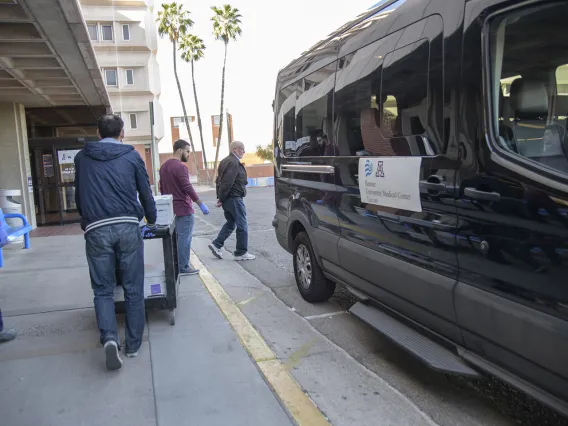 Lab Techs stand by before loading the kits into a Banner van as local media prepares to film.