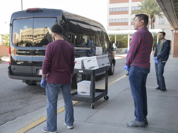 Lab Techs stand by before loading the kits into a Banner van as local media prepares to film.