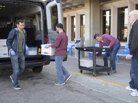 Lab Techs stand by before loading the kits into a Banner van as local media prepares to film.