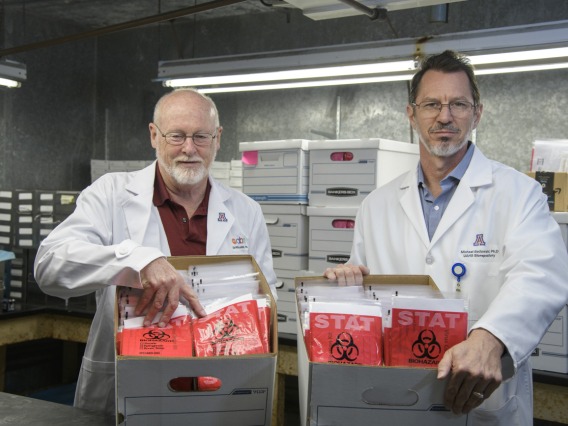 David T. Harris, PhD, (left) and Michael Badowski, PhD, (right) created sample collection kits to help alleviate the shortage of COVID-19 testing capabilities in March and April. The kits shown are ready for delivery to Arizona health care providers to test patients for COVID-19. The group was planning to produce approximately 5,000 sample collection kits per week, and delivered 1,000 of them to Banner-University Medical Center Tucson in early April.