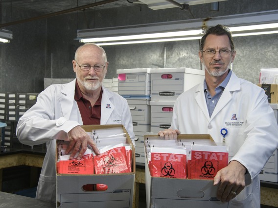 David T. Harris, PhD, (left) and Michael Badowski, PhD, (right) stand in a freezer with sample collection kits ready for delivery to Arizona health care providers.