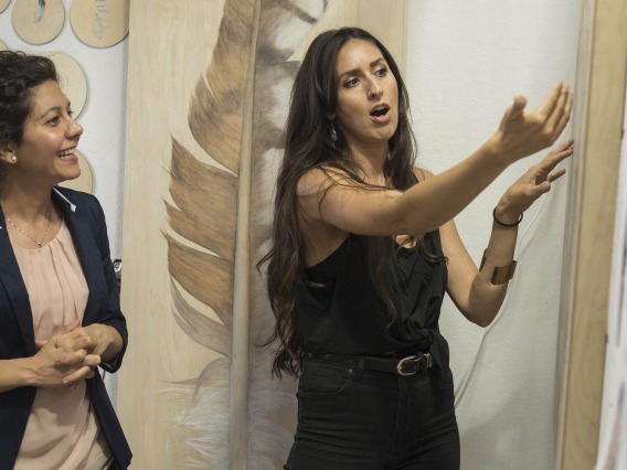 Alexandra “Lexie” Bowers, a wood burning and mixed media artist, shows Shirin Doroudgar, PhD, an assistant professor at the College of Medicine – Phoenix, the progress she has made on the art inspired by Dr. Doroudgar’s heart cell research.