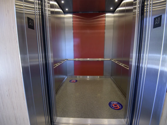 Decals placed on elevator floors mark six feet, helping visualize appropriate distance.