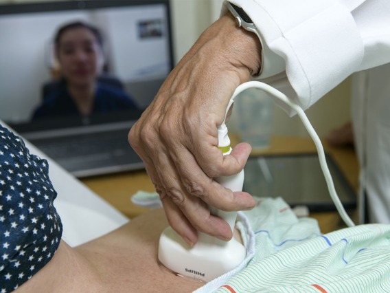Working with a “standardized patient,” a specialist who portrays patients when health care providers train in new procedures, a doctor learns how to perform bedside lung ultrasound. The physician would wear gloves when treating patients.
