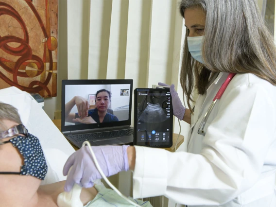 Dr. Elaine Situ-LaCasse (pictured on the laptop) receives a livestream of the exam results and assists in diagnosing a standardized patient during a telehealth training consultation with Julia Brown, MD, emergency department medical director at the Copper Queen Community Hospital in Bisbee, Arizona.