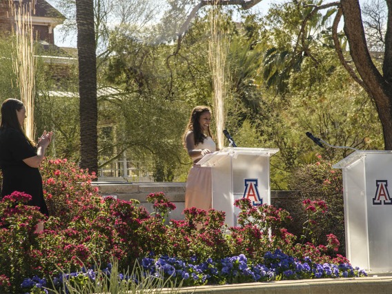 Faith Dickerson announces that she matched for general surgery at the University of Wisconsin as sparks fly behind her at the UArizona College of Medicine – Tucson 2022 Match Day event.
