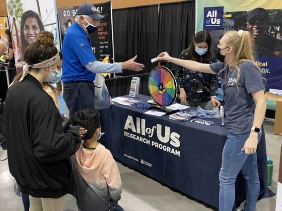 Marissa McLelland (right) an engagement coordinator with All of Us UArizona – Banner, talks with people interested in the program while she hands out information and branded hand sanitizer. 