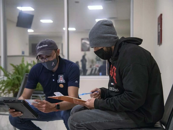 Zuckerman College of Public Health student José Angel Almeida (left) helps Oscar Moreno with his initial intake for registration at a COVID-19 vaccine clinic hosted April 23 by UArizona Health Sciences at the Consulate of Mexico in Douglas, Arizona.