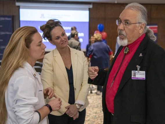 Dr. Carlos Gonzales speaks with Primary Care Physician scholarship recipient Hannah Shy, left, and her mother, center.