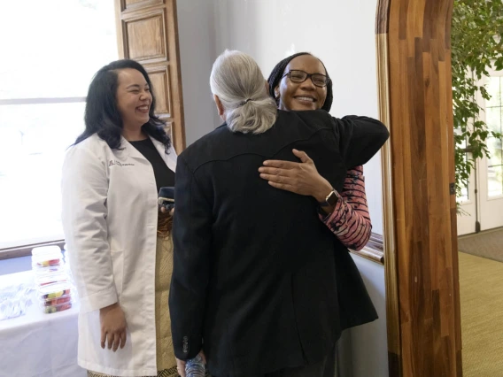 Primary Care Physician scholarship recipient Kaloni Philipp smiles as Dr. Carlos Gonzales congratulates scholarship recipient Beverley Trutter. 