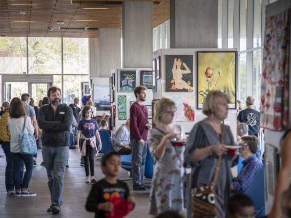 Attendees mingle in the Bioscience Research Laboratories lobby during the 10th annual “On Our Own Time” art exhibit, featuring art made by University of Arizona employees and their immediate family members.