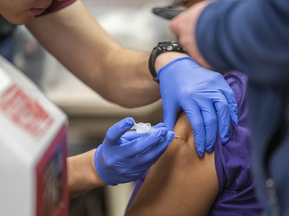 A Street Medicine Phoenix student volunteer administers the flu vaccine to a patient.