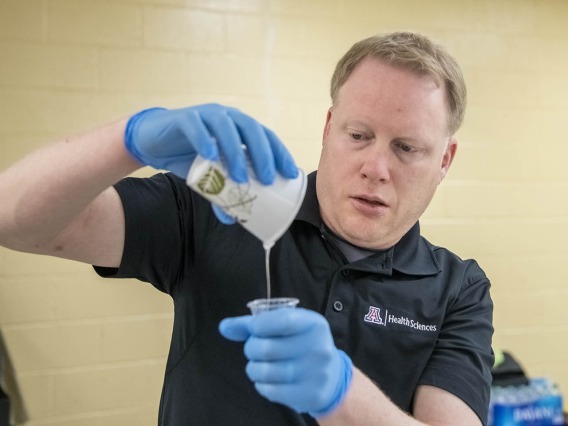 David Biffar, ASTEC’s assistant director of operations, pours liquid latex into a cup to prepare for the creation of the next volunteer’s wound.