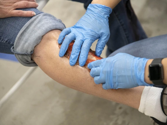 Merryl Lopido, simulation operations specialist for ASTEC, pats down a simulated wound on Helen Ward’s leg. TPD volunteers like Ward will be triaged by first responders based on the severity of their simulated injuries.