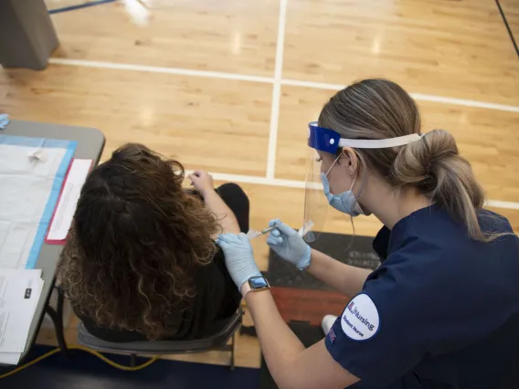 After taking a COVID-19 antigen test, a student receives a flu shot from College of Nursing student Genevieve Veneziale, who says the secret to giving a good shot is “remaining calm and talking to your patient, making sure they stay calm and making sure they’re relaxed.”