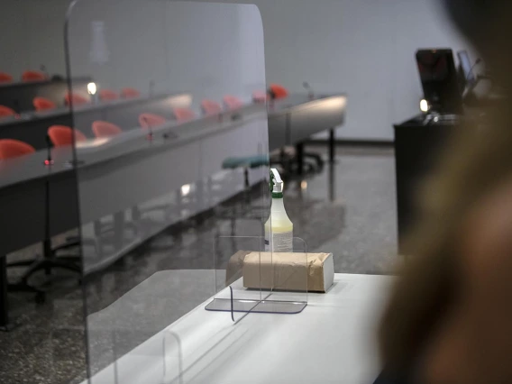 In a large lecture hall, a plastic barrier has been installed to reduce the spread of aerosolized droplets that could carry viruses and other bugs.