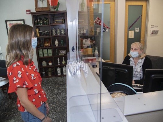 Newly installed plastic barriers protect staff and visitors in a reception area in Drachman Hall. From left: Ali Bridges, College of Pharmacy director of communication, and administrative assistant Amy Dorgan.