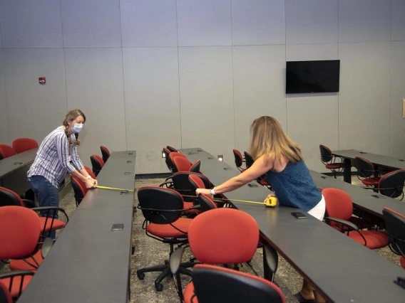 Mary Matthews (left) and Angie Souza (right) of Health Sciences Planning and Facilities measure the distance between desks in a Drachman Hall classroom to ensure students stay six feet apart.