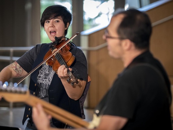 Two-Door Hatchback’s Samantha Bounkeua sings and plays violin in a performance for The Tucson Studio on the Health Sciences campus in Tucson.