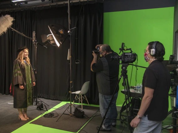 The five Health Sciences colleges planned special ways to mark the rite-of-passage of earning a degree, despite social distancing and stay-at-home orders in May. Medical student Bethany Boczar wears her regalia for a studio shoot in the Health Sciences Innovation Building as Biocommunications photographer Mitchell Masilun and videographer Gilberto Vega film for the College of Medicine – Tucson’s virtual convocation ceremony.