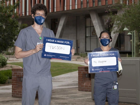 Third-year College of Medicine – Tucson students Asha Esprit and Brianna Dolana stand outside of the Health Sciences Innovation Building in Tucson. Esprit wears a mask for Tucson and Dolana wears a mask for her daughter. 