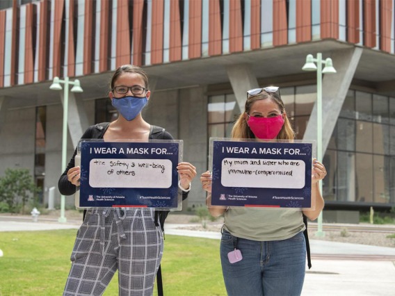 Jacqueline Sanchez  and Alyssa Cordova, College of Medicine – Tucson research technicians, hold their signs in front of the Health Sciences Innovation Building in Tucson. Sanchez and Cordova are graduate students in the Postbaccalaureate Research Education Program at the University of Arizona (PREP@UAZ ), which provides American Indian/Alaskan Native students with a rigorous research and educational foundation to prepare them for biomedical doctorate programs. 