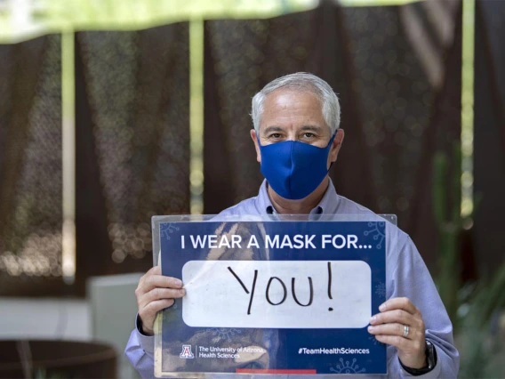 Tony Malaj, executive director of campus management and operations of UArizona’s Phoenix Biomedical Campus, holds a sign that reads, “I wear a mask for you!”