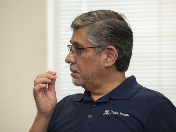 Rodrigo Silva, DVM, MPH, adjunct professor at the Mel & Enid Zuckerman College of Public Health in Phoenix, administers the COVID-19 antigen test by placing a swab inside his nostril to collect a sample. 