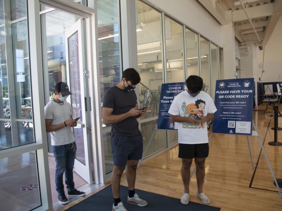 University of Arizona students inside the NorthREC facility, at the Honors Village in Tucson, use their phones to register for COVID-19 antigen testing.