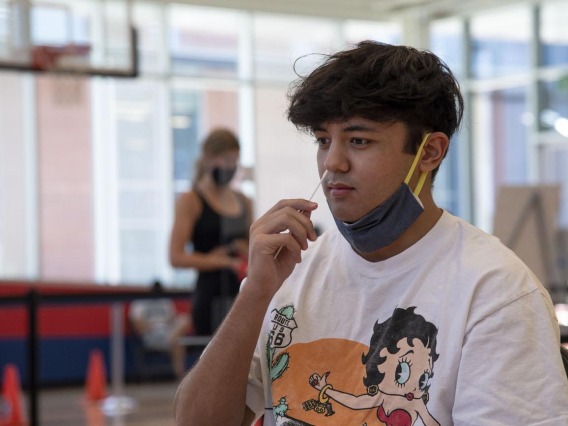 University of Arizona student Mason Young inserts a nasal swab into his nose. The COVID-19 test was required for all dormitory residents and remains available to students and staff.
