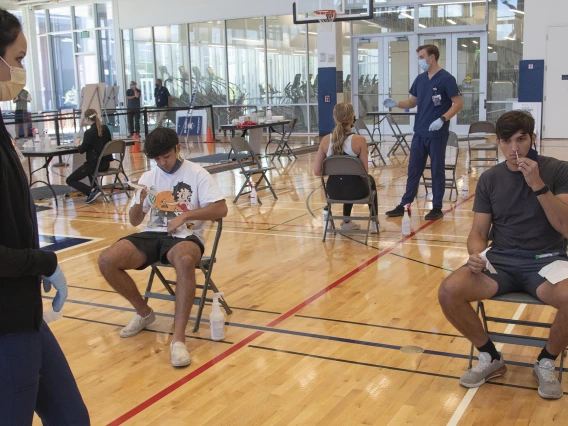 Clinical research coordinator Brenna Abril instructs students in self-administering the nasal swab antigen test at the Recreation and Wellness Center, known as NorthREC, in Tucson.