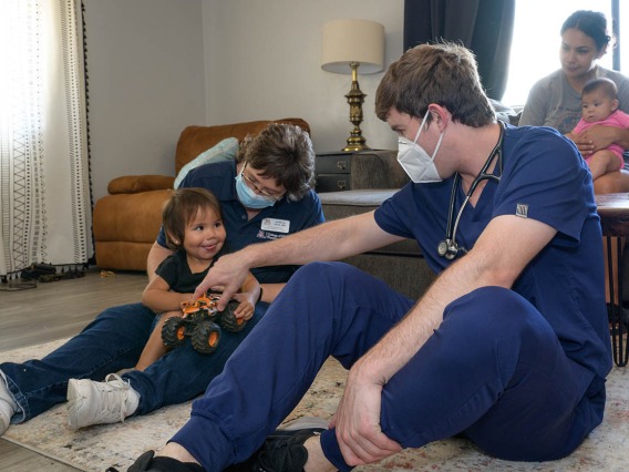 Judith Hunt, MD, and medical student Jeremy Winkleman play with Amara Lopez to set her at ease during a home health visit.