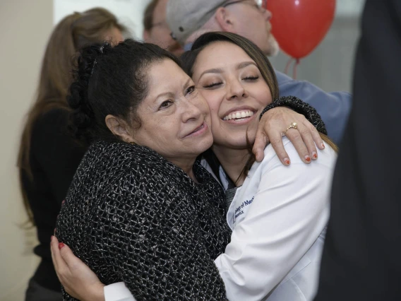 A family member congratulates Primary Care Physician scholarship recipient Abigail Solorio with a hug.