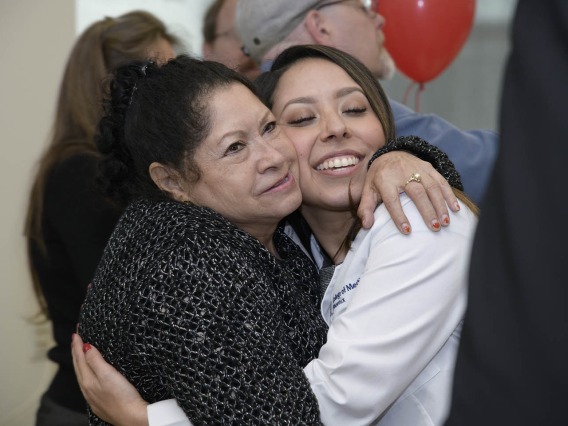 A family member congratulates Primary Care Physician scholarship recipient Abigail Solorio with a hug.