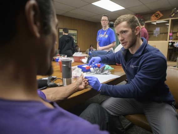 Street Medicine Phoenix co-founder Justin Zeien prepares to test a patient’s blood sugar levels with a finger prick. 