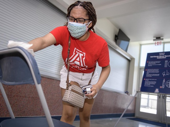 A student sanitizes her seat after completing a self-administered nasal swab antigen test for COVID-19 at McKale Center in Tucson. 