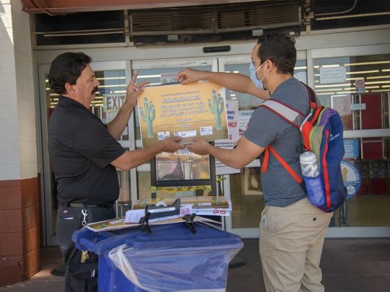 Assistant Store Manager Peter Ramirez and fourth-year medical student Ricardo Reyes hang a social distancing sign outside a Food City grocery store on South Sixth Avenue in Tucson as part of an outreach campaign about social distancing.