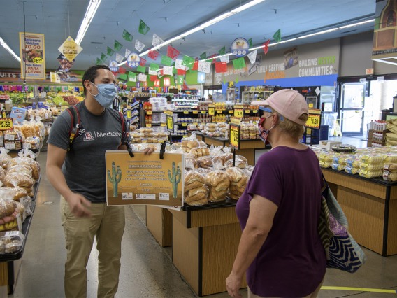 Fourth-year medical student Ricardo Reyes speaks with a customer at a Food City grocery store in Tucson about the social distancing campaign he and his classmates are hoping to share with the Spanish-speaking community.