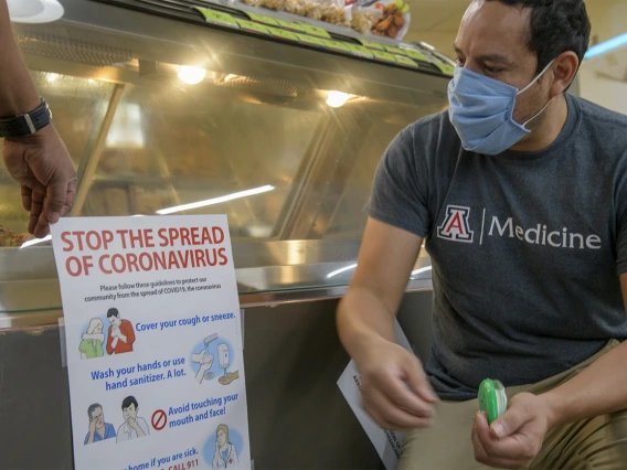 Fourth-year medical student Ricardo Reyes helped create these posters and then hang them in a Tucson grocery store.