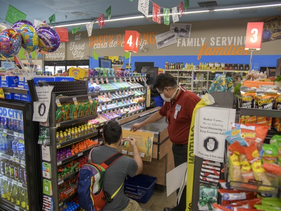 Fourth-year medical student Ricardo Reyes and Store Manager Ramon Lopez hang a social distancing poster at the end of a grocery check-out aisle at a Food City grocery store on West Ajo Way in Tucson.